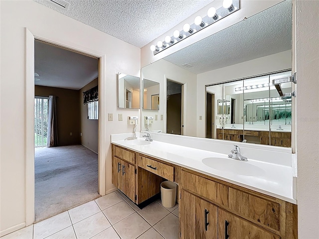 bathroom featuring a textured ceiling, double vanity, a sink, and tile patterned floors