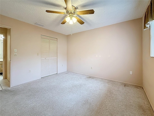 unfurnished bedroom featuring a textured ceiling, a closet, visible vents, and light colored carpet