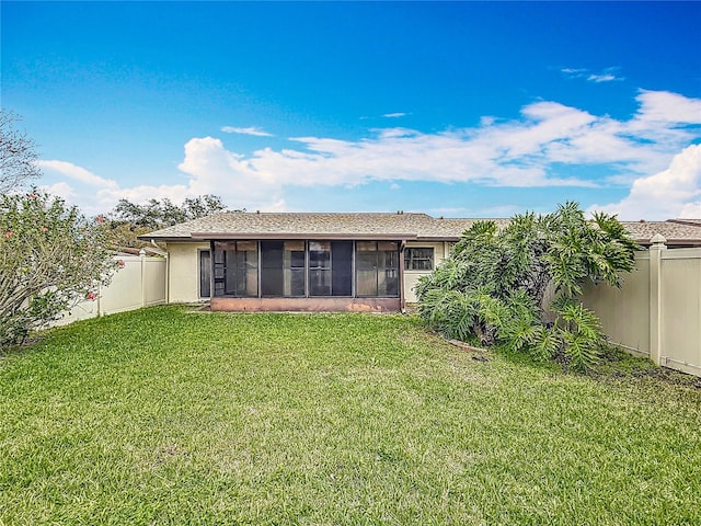 rear view of property with a sunroom, a fenced backyard, a yard, and stucco siding