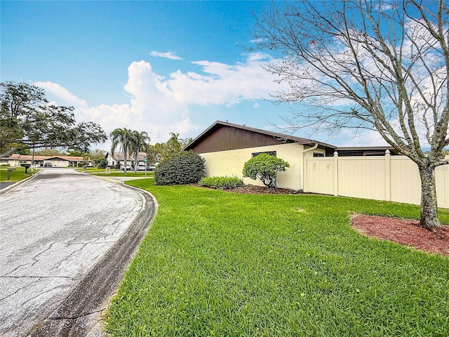 view of side of property featuring fence and a yard