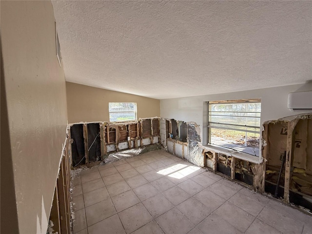 empty room with vaulted ceiling, a textured ceiling, and a wall mounted air conditioner