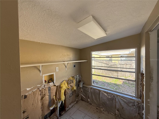 interior space featuring vaulted ceiling, a textured wall, and a textured ceiling