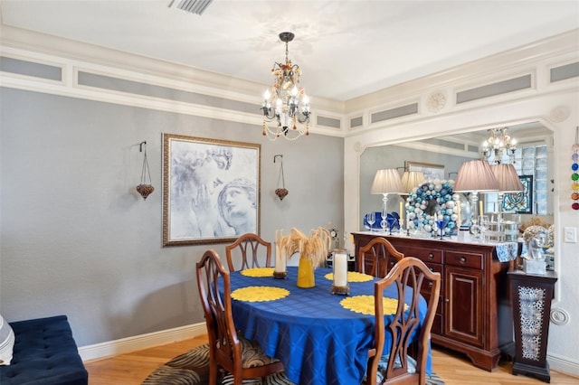 dining area with light wood finished floors, visible vents, baseboards, crown molding, and a chandelier