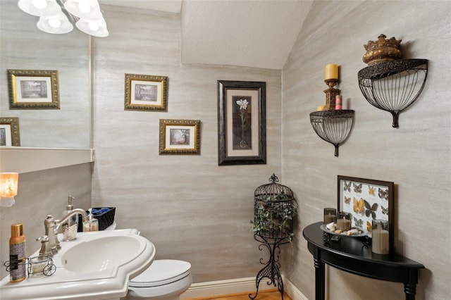 bathroom featuring a notable chandelier, a sink, toilet, and baseboards