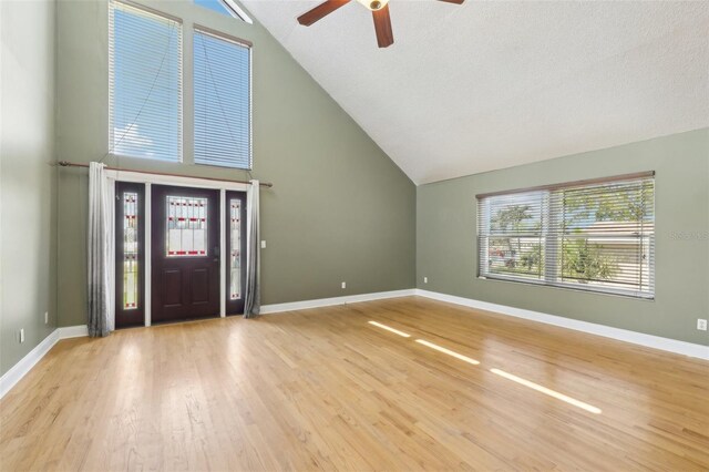 foyer with high vaulted ceiling, a ceiling fan, baseboards, and wood finished floors