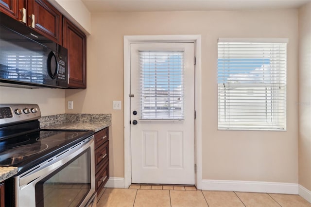 kitchen with black microwave, light tile patterned floors, light stone countertops, and stainless steel electric stove