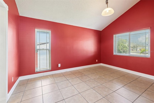 spare room featuring vaulted ceiling, light tile patterned floors, a textured ceiling, and baseboards