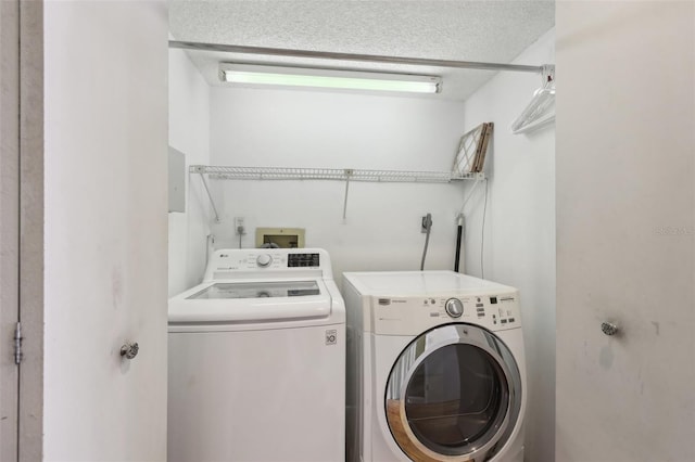 clothes washing area featuring a textured ceiling, laundry area, and washer and dryer