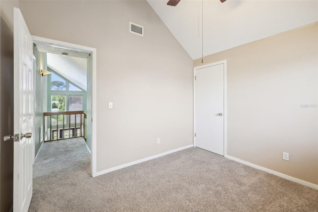 carpeted spare room with high vaulted ceiling, visible vents, and baseboards