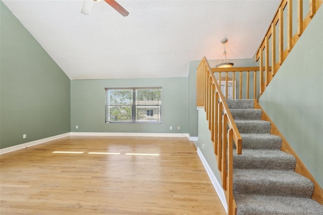 stairway featuring lofted ceiling, baseboards, and wood finished floors