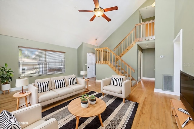 living room with baseboards, visible vents, stairway, light wood-type flooring, and high vaulted ceiling