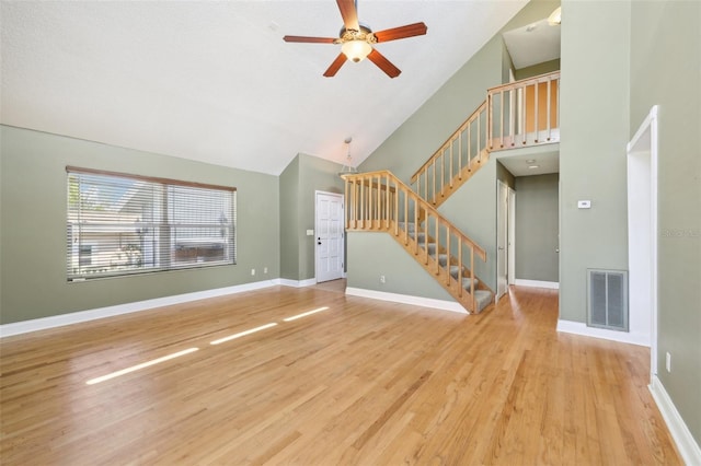 unfurnished living room featuring high vaulted ceiling, wood finished floors, visible vents, baseboards, and stairs