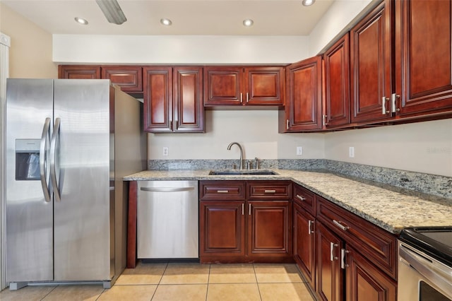 kitchen featuring a sink, light stone countertops, appliances with stainless steel finishes, and dark brown cabinets