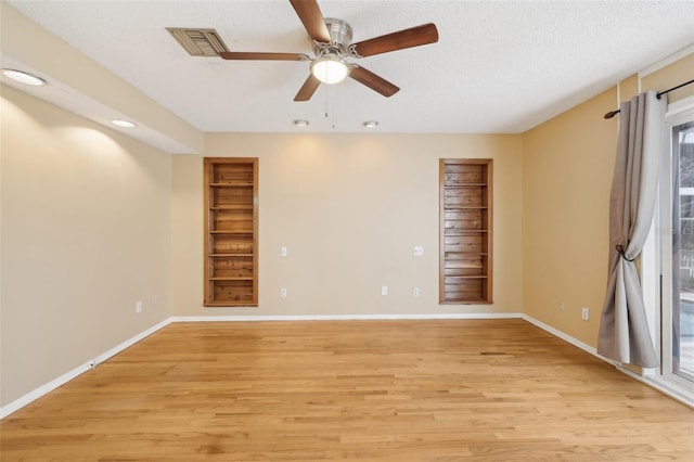 empty room with light wood-type flooring, baseboards, and visible vents