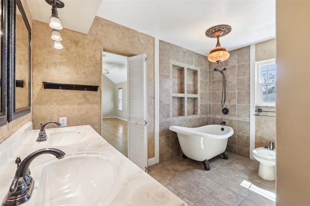 full bath with a sink, a freestanding tub, tile walls, and tiled shower