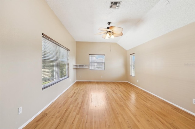 spare room featuring baseboards, light wood-type flooring, visible vents, and a healthy amount of sunlight