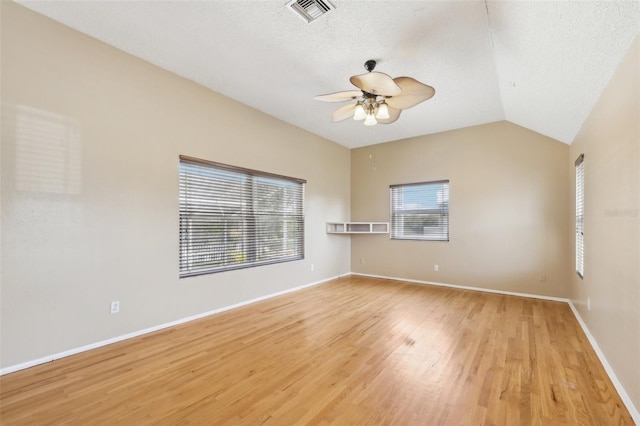 unfurnished room with light wood finished floors, baseboards, visible vents, and vaulted ceiling