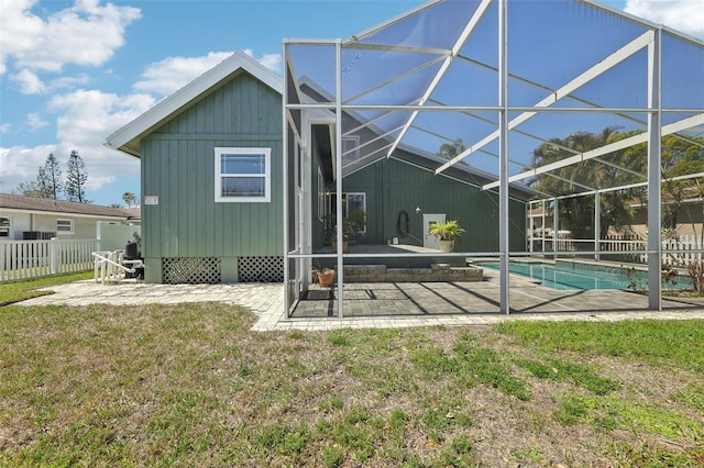 rear view of house with a fenced in pool, glass enclosure, a patio area, and fence