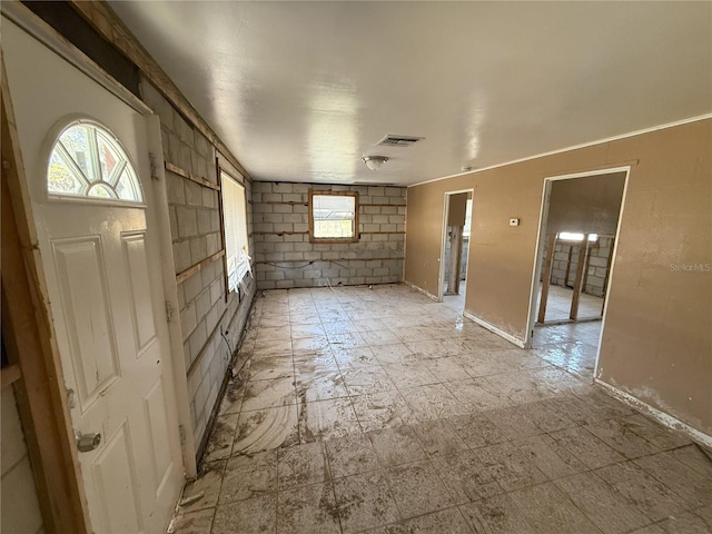 empty room featuring concrete block wall and visible vents