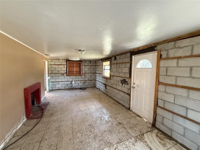 unfurnished living room featuring concrete block wall and light floors