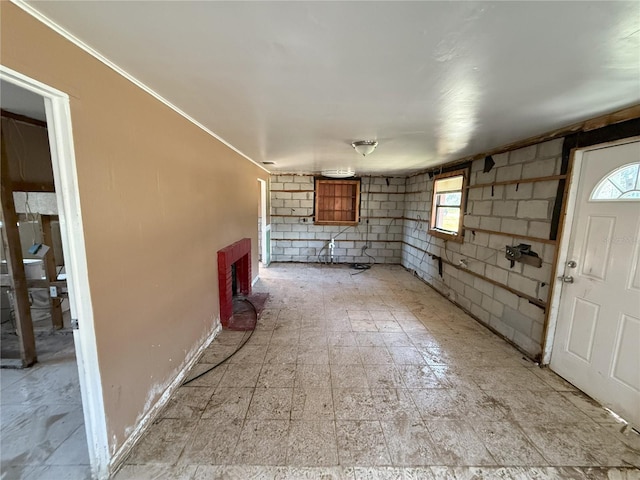 unfurnished living room with ornamental molding, plenty of natural light, and baseboards