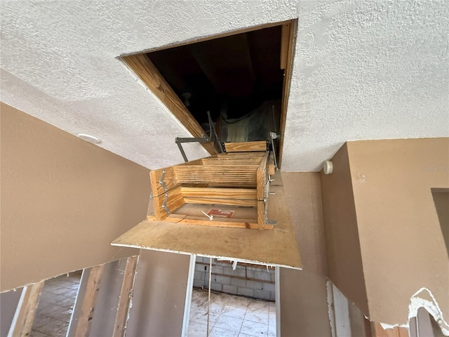 stairs featuring a textured ceiling