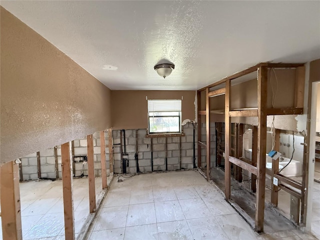 miscellaneous room featuring a textured ceiling and a textured wall