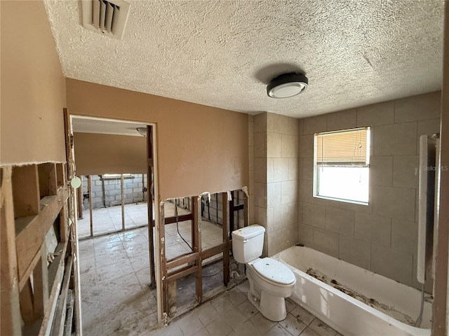 bathroom with toilet, visible vents, a shower, and a textured ceiling