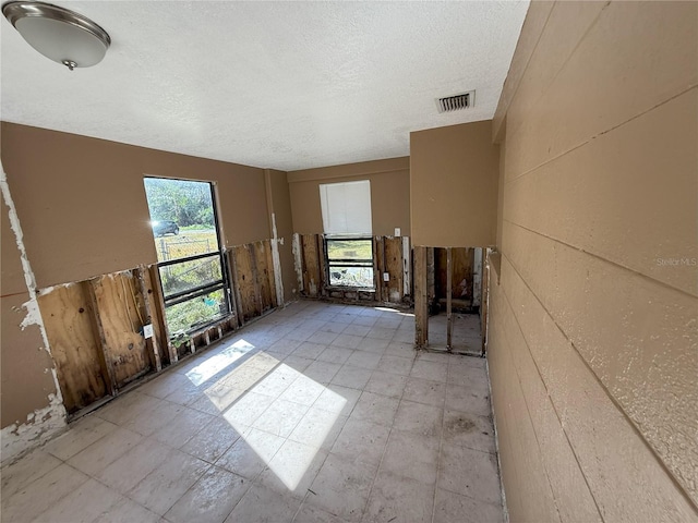 spare room with a textured ceiling, light floors, and visible vents