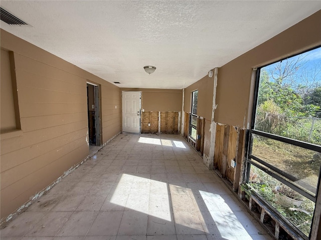 spare room with light floors, visible vents, and a textured ceiling