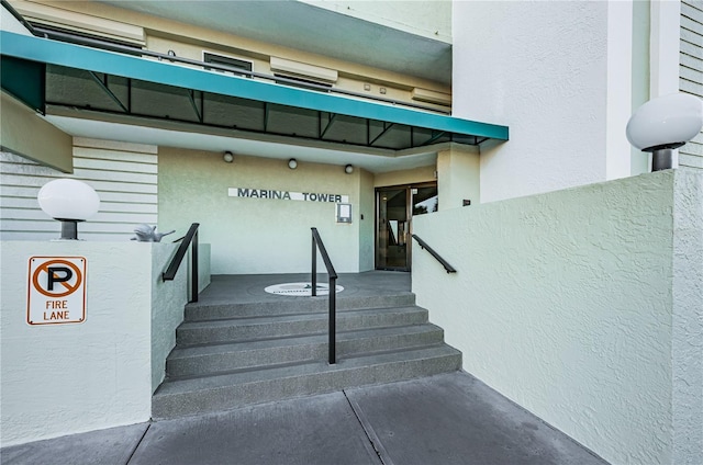 view of exterior entry featuring an AC wall unit and stucco siding