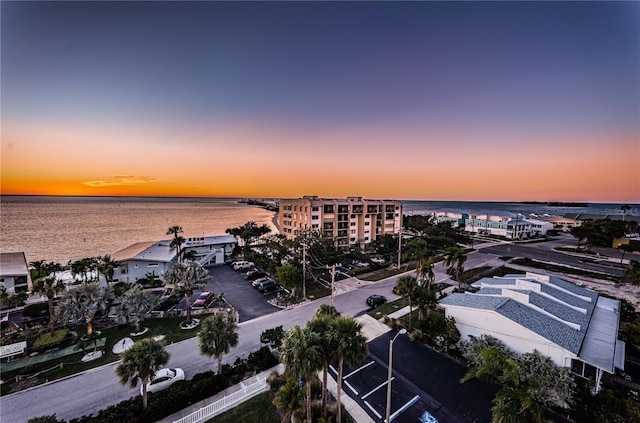 aerial view at dusk featuring a water view