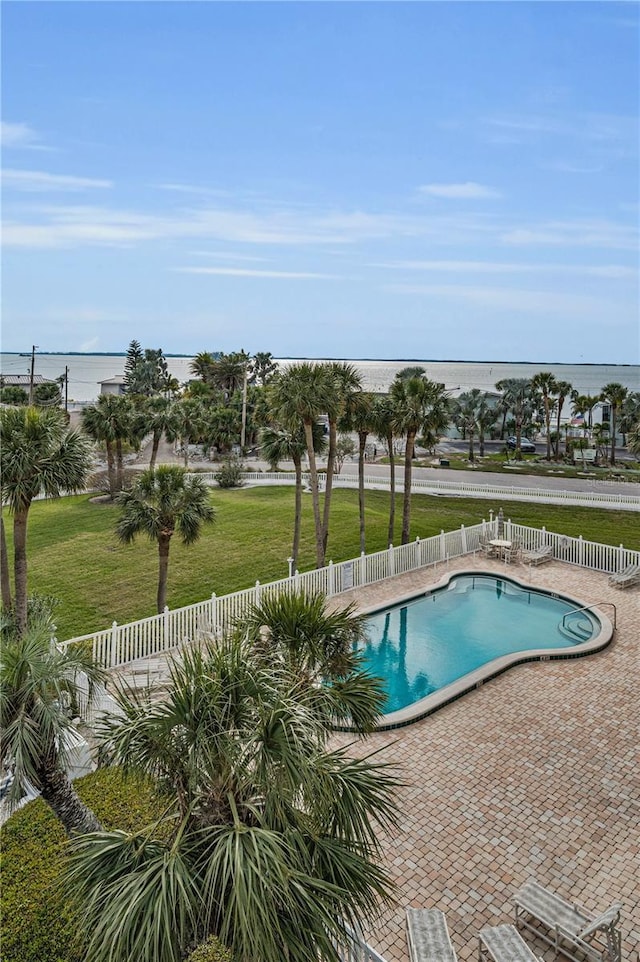 community pool featuring a fenced backyard, a yard, a patio, and a water view