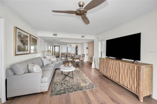 living area featuring crown molding, visible vents, ceiling fan, and wood finished floors