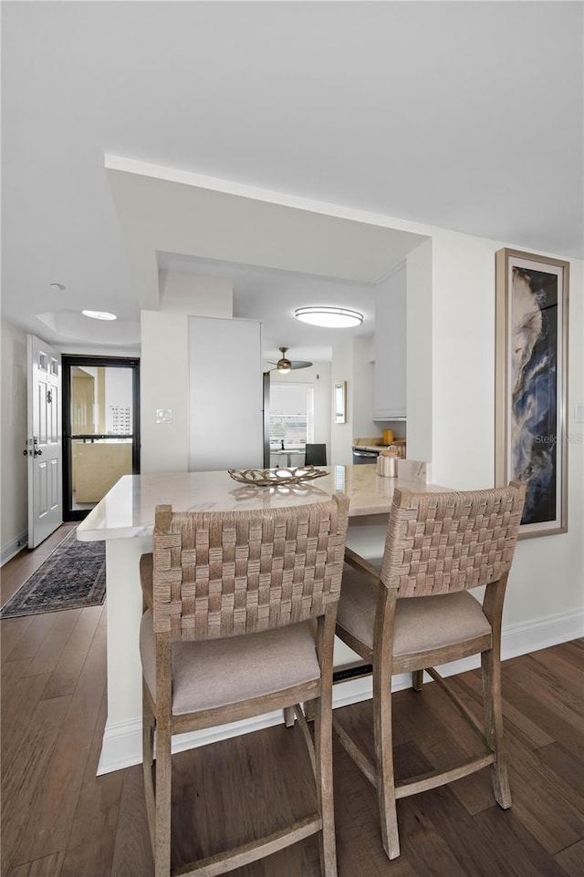 kitchen featuring baseboards, dark wood-style flooring, a peninsula, light countertops, and white cabinetry