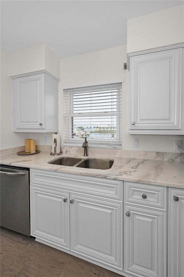 kitchen with white cabinets, dishwasher, a sink, and light stone countertops