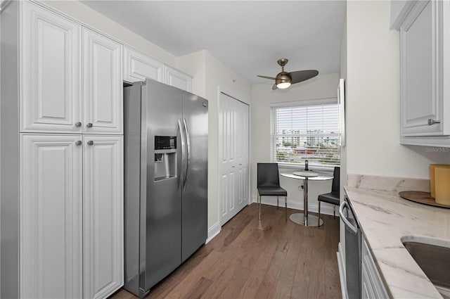 kitchen with a ceiling fan, white cabinetry, appliances with stainless steel finishes, light stone countertops, and dark wood finished floors