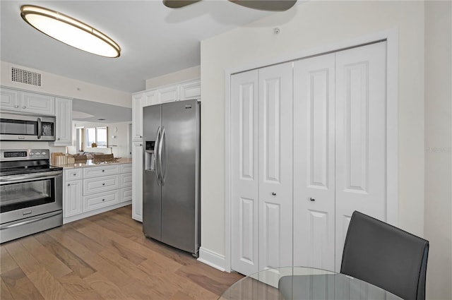 kitchen with appliances with stainless steel finishes, light wood-type flooring, visible vents, and white cabinets