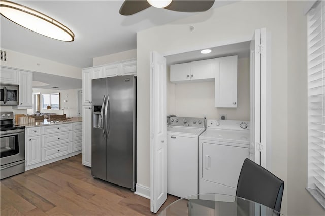 kitchen featuring stainless steel appliances, washer and dryer, white cabinetry, and light wood-style floors