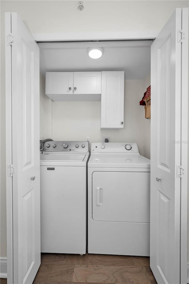 washroom with separate washer and dryer, dark wood-style flooring, and cabinet space