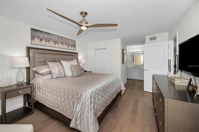 bedroom featuring visible vents, ensuite bathroom, ceiling fan, wood finished floors, and baseboards