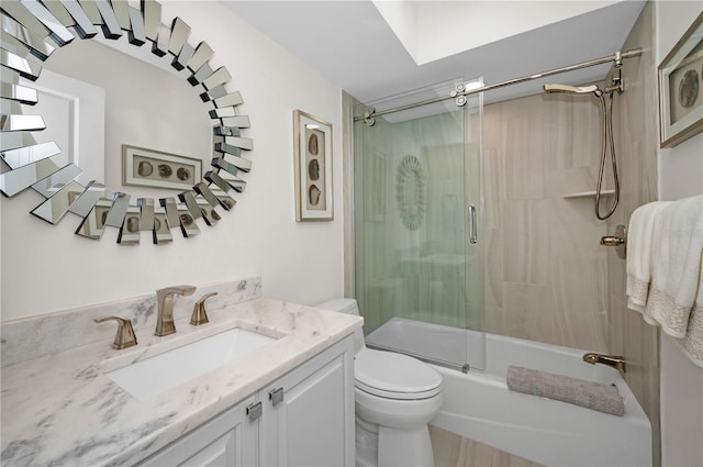 full bath featuring toilet, shower / bath combination with glass door, and vanity