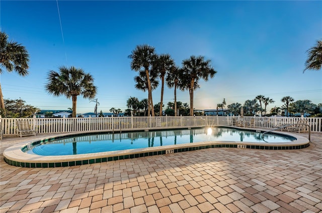 community pool with a patio area and fence