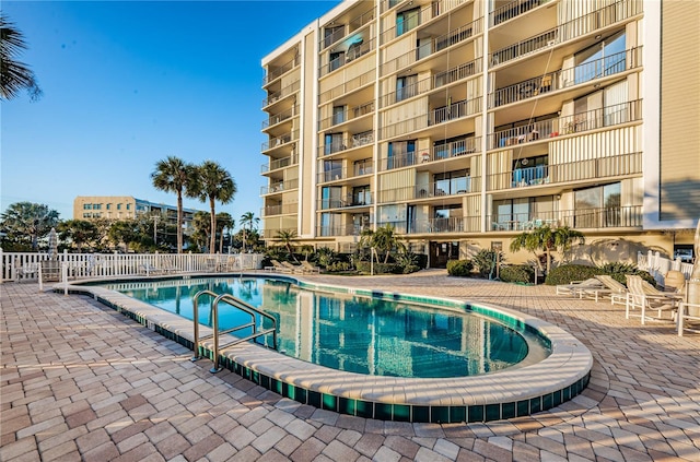 community pool with a patio and fence