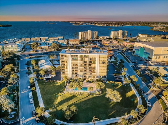 aerial view at dusk featuring a water view and a city view