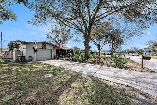 view of front of property with a front lawn, concrete driveway, fence, and an attached garage