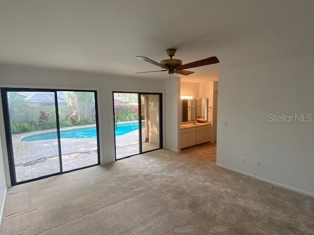 unfurnished room featuring baseboards, ceiling fan, and light colored carpet