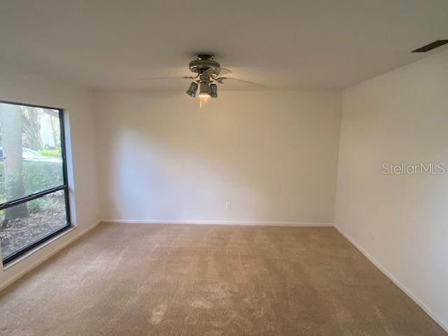 carpeted spare room with visible vents, ceiling fan, and baseboards