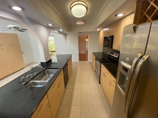 kitchen with light tile patterned floors, a raised ceiling, crown molding, black appliances, and a sink