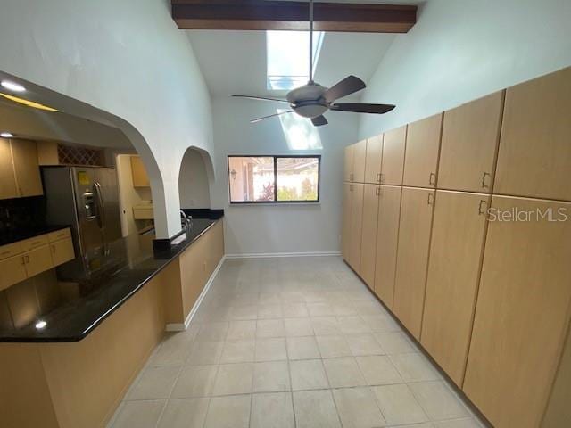 kitchen with dark countertops, stainless steel fridge, high vaulted ceiling, and beamed ceiling